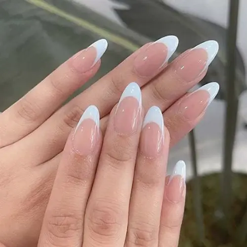 A close-up of a stylish French nails design featuring glossy white tips on a soft pink base, adorned with delicate silver accents, displayed against a sleek marble background.