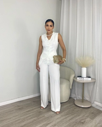 Mulher estilosa com look de guarda-roupa cápsula feminino, vestindo camiseta branca, calça jeans e tênis, em um ambiente minimalista.