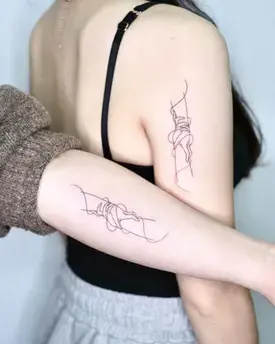 
Two wrists with matching friendship tattoos featuring interlocking heart designs, symbolizing a strong bond between best friends.