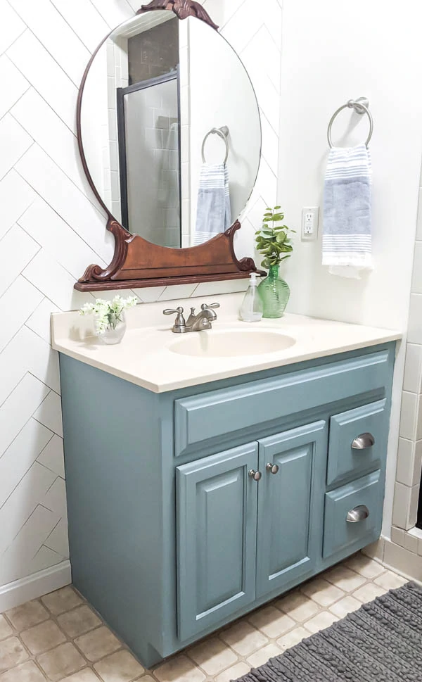 A freshly painted bathroom vanity in white, featuring a smooth finish with paint rollers and brushes nearby, showcasing a DIY paint-a-bathroom-vanity project.